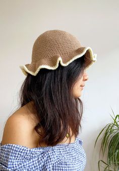 a woman wearing a brown hat with scalloped brimmings on her head