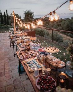 a long table filled with lots of food on top of a wooden table covered in lights