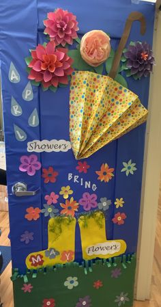 a blue door decorated with paper flowers and umbrellas on the front, says shower bring spring