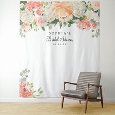 a chair sitting in front of a white wall with flowers on it and the name banner behind it