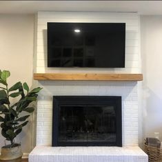 a fireplace with a flat screen tv mounted on the wall and a potted plant next to it