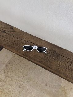 a pair of sunglasses sitting on top of a wooden bench next to a tiled floor