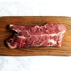 two pieces of raw meat sitting on top of a wooden cutting board