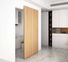 an open door to a kitchen with white cabinets and wood accents on the doors, in front of a countertop