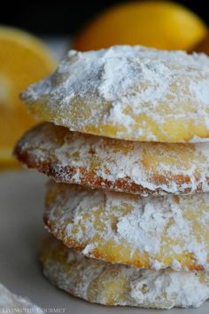 three lemon filled donuts stacked on top of each other with powdered sugar and oranges in the background