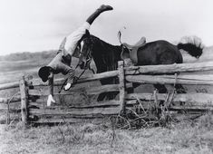 a man falling off his horse over a wooden fence