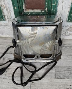 an old silver toaster sitting on top of a wooden floor next to a door