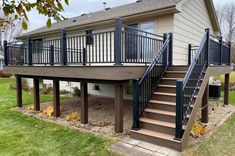 a deck with stairs and railings in front of a house