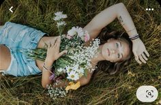 a woman laying in the grass with flowers on her chest and hands behind her head