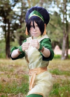 a woman dressed in green and yellow posing for the camera with her fist raised up