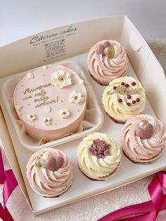 a box filled with pink cupcakes on top of a white table covered in pink ribbon