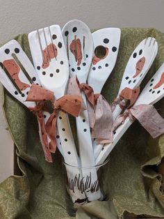 a bunch of white and brown utensils in a cup on a green cloth