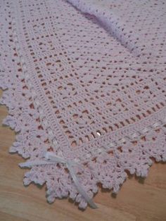 a crocheted blanket is laying on the floor with white ribbon around it's edge