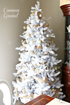 a white christmas tree with gold and silver ornaments