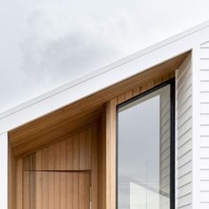 an open window on the side of a white building with wood trimmings and slats