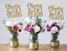 three vases filled with flowers on top of a wooden table