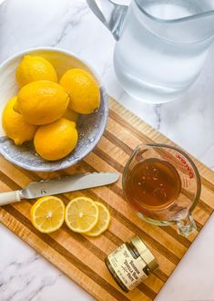 a bowl of lemons and some honey on a cutting board