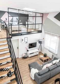 an aerial view of a living room with stairs and couches in the foreground