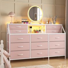 a pink dresser with drawers and a mirror on the top, in front of a beige wall