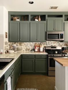 a kitchen with green cabinets and white counter tops