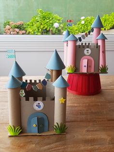 two paper castles sitting on top of a wooden table