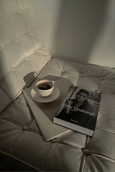 a cup of coffee sitting on top of a white book next to a black and white photo