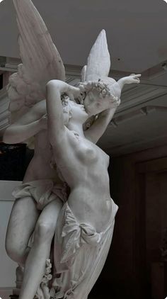 two statues in the shape of cupid and cherubs with their arms around each other