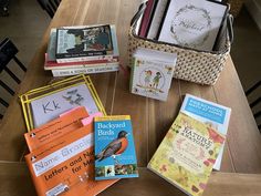 many books are sitting on a table with a basket full of children's books