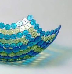 a blue and green bowl sitting on top of a white tablecloth with buttons in it