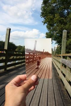 someone holding up a photo on a bridge