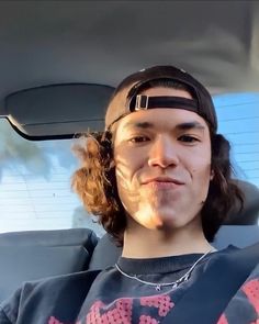 a man sitting in the back seat of a car with his tongue out and wearing a bandana