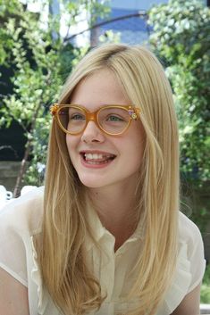 a woman wearing glasses and smiling for the camera