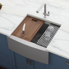 a kitchen sink with a cutting board and knife in the bottom drawer next to it