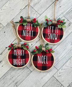 three christmas ornaments hanging from twine on wooden planks with holly and red berries