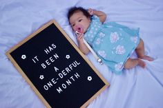 a baby is laying next to a sign that says it has been a one - derful month