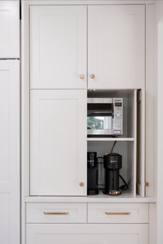 a kitchen with white cabinets and gold pulls on the doors, including a coffee maker