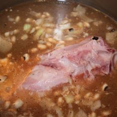 the meat is being cooked in the pot with some broth and spices around it