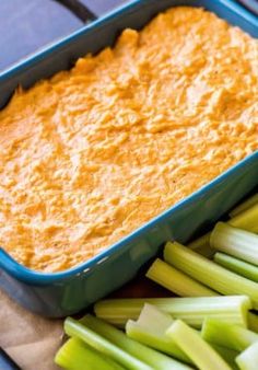 carrot dip in a blue casserole dish with celery and celery stalks