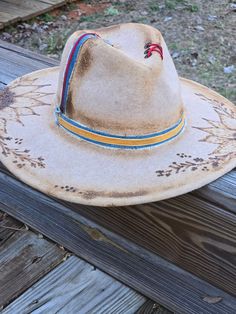 An absolutely stunning, custom burned sunflower fedora. This hat is a beautiful tan felt with accents of bluejean and red leather!  This would be a great addition to any outfit whether you dress up or down! Vintage Fedora For Festival, Vintage Fitted Fedora For Festival, Fitted Vintage Fedora For Festival, Country Style Fedora Felt Hat For Festival, Custom Fedora Felt Hat For Country Events, Custom Fedora Felt Hat For Festivals, Custom Fedora For Fall Country Events, Custom Felt Hat For Fall Country Events, Artisan Fitted Fedora For Festivals