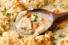 a wooden spoon scooping some food out of a casserole dish with broccoli and cauliflower