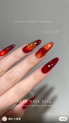 a woman's hand with red and gold nail polish on it, holding up her nails