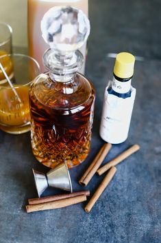 an assortment of different types of liquors on a table with cinnamon sticks and bottles