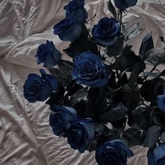 a bouquet of blue roses sitting on top of a white cloth covered bed sheet,