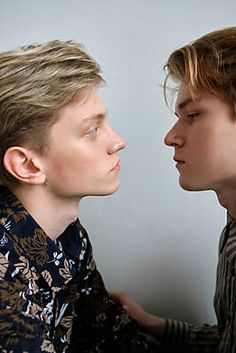 two young men are facing each other and one is looking at the other man's face