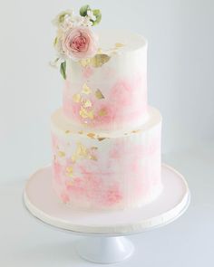 a three tiered cake with pink and white flowers on the top is sitting on a plate