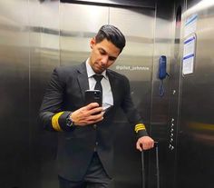 a man in a suit and tie using his cell phone while standing next to an elevator