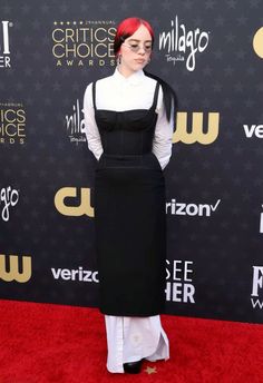 a woman in black and white dress standing on red carpet with her hands behind her back