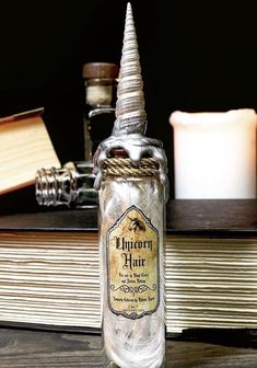 a glass bottle with a fake unicorn's horn sitting on top of an open book