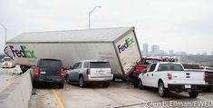 several cars are parked in front of a fedex truck that has been flipped over