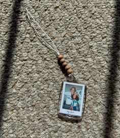 a necklace with a photo hanging from it's side on a carpeted surface